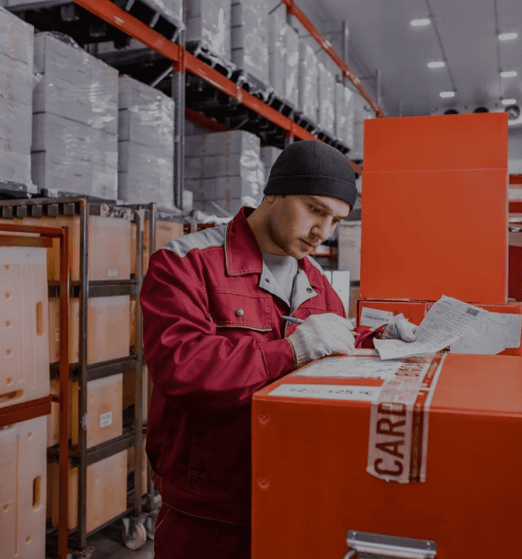 Работник склада Biocard на фоне стеллажа с грузами. Biocard - перевозки грузов с температурным режимом по РФ и миру.